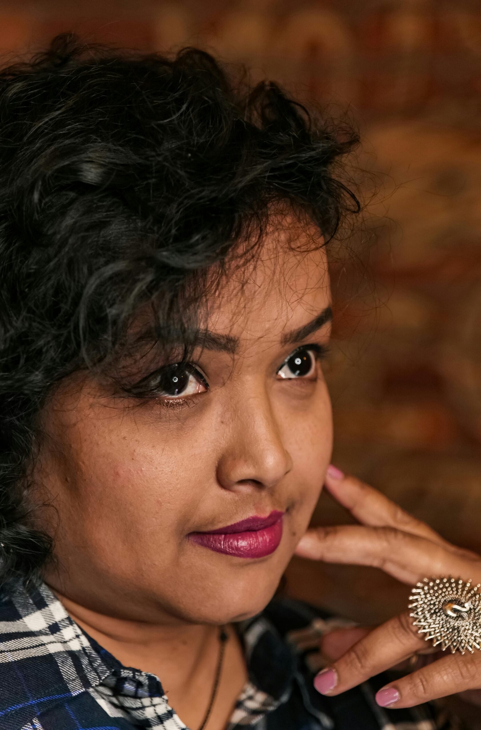 Close-up portrait of a woman with curly hair and striking jewelry, showcasing beauty and elegance.