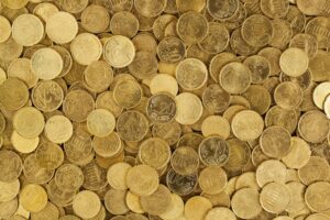 A close-up shot of Euro coins scattered in a pile, showcasing a rich golden texture.